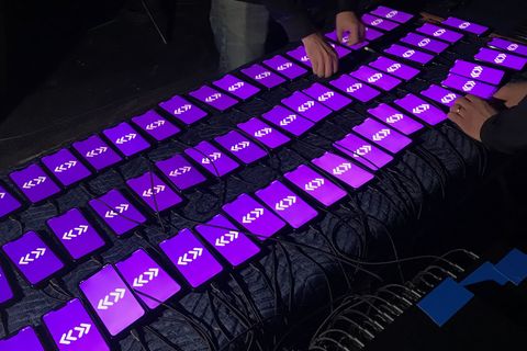 Dozens of phones on a padded table, every screen showing the same purple pattern.